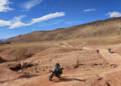 Group of ADV riders crossing open desert trails in a wide rocky valley in Morocco.