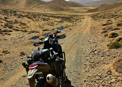 Adventure motorcycle on a remote dirt track across the Moroccan high plateau.