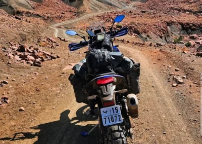 Adventure motorcycle on a rocky dirt track winding through the Moroccan mountains.