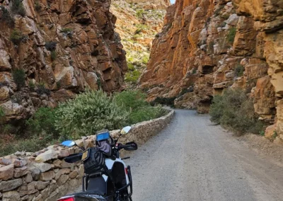 Adventure motorcycle parked on a gravel road through a narrow rocky canyon in South Africa.