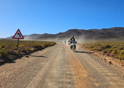 Adventure riders travelling on a dusty gravel road in South Africa.