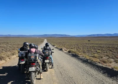 Three adventure riders stopped on a remote gravel road in South Africa.